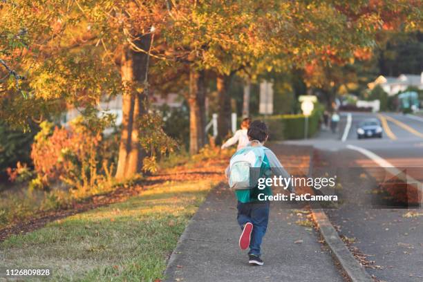 elementary-age classmates running to school with their backpacks - school district stock pictures, royalty-free photos & images