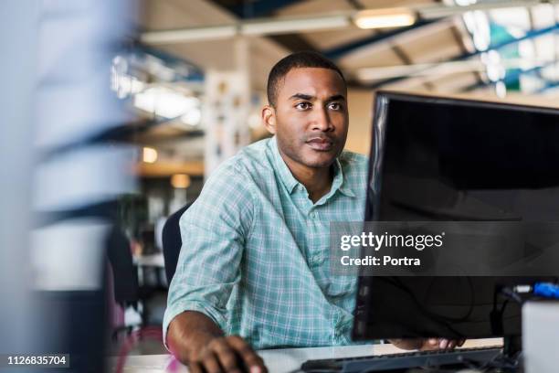 young businessman using computer at desk - computer guy stock pictures, royalty-free photos & images