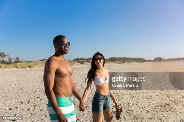 ビーチで手をつないで幸せなカップル - hot pants ストックフォトと画像