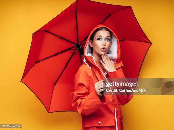 mädchen mit roten regenschirm - frau mit gelben regenmantel stock-fotos und bilder