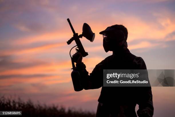 silhouette of a paintball player - paintball stock pictures, royalty-free photos & images