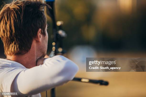 young man practicing archery - archery competition stock pictures, royalty-free photos & images