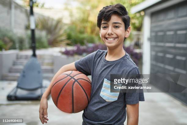 portret van lachende jongen met basketbal staande in tuin - 10 11 jaar stockfoto's en -beelden
