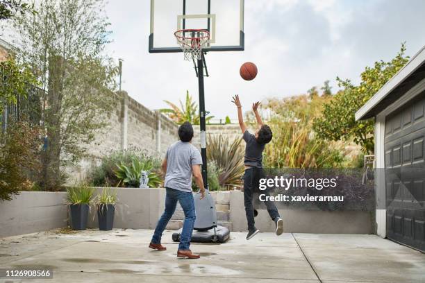 father looking at son playing basketball in yard - atirar ao cesto imagens e fotografias de stock