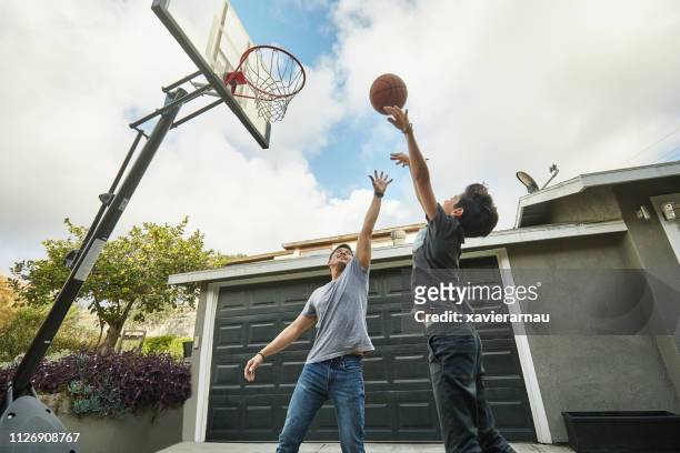father blocking while son making basketball score - blocking sports activity stock pictures, royalty-free photos & images