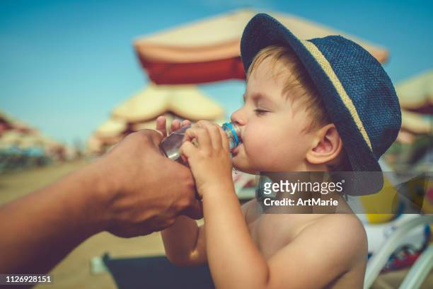 kind drinkwater op het strand op zomer roepingen - hot boy pics stockfoto's en -beelden
