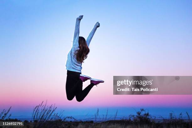 young woman jumping raising her arms at a colorful sunset - aragon, spain - woman achievement stock pictures, royalty-free photos & images