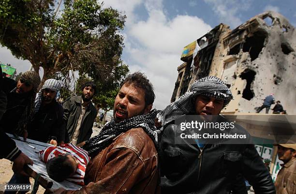 Libyan rebel fighters carry out a comrade wounded during an effort to dislodge some ensconced government loyalist troops who were firing on them from...