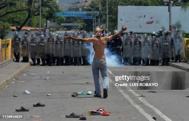 Demonstrator gestures in front of Venezuelan national policemen standing guard at the Simon Bolivar international bridge, in Cucuta, Colombia after...