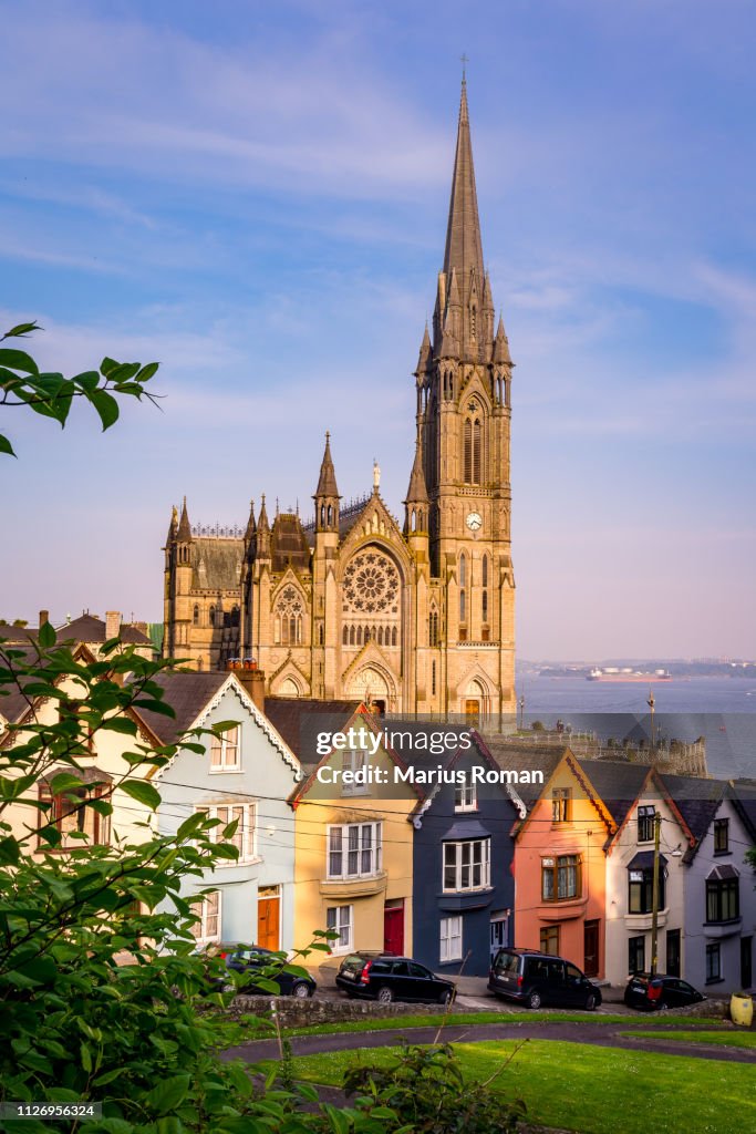 Row of colorful houses with cathedral background in Cobh, County Cork, Ireland.