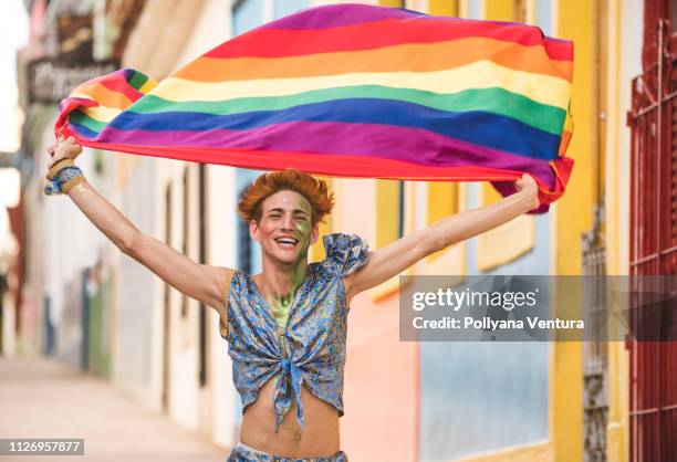 gay mann läuft mit regenbogenfahne - pride fest stock-fotos und bilder