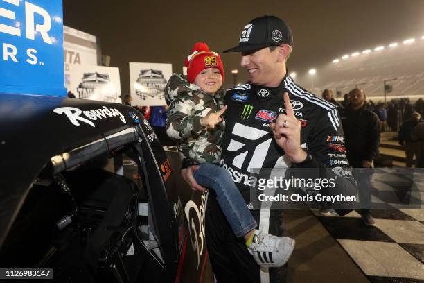 Kyle Busch, driver of the Cessna Toyota, celebrates with his son Brexton by placing the Winner's sticker on his car after winning the NASCAR Gander...