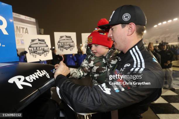 Kyle Busch, driver of the Cessna Toyota, celebrates with his son Brexton by placing the Winner's sticker on his car after winning the NASCAR Gander...