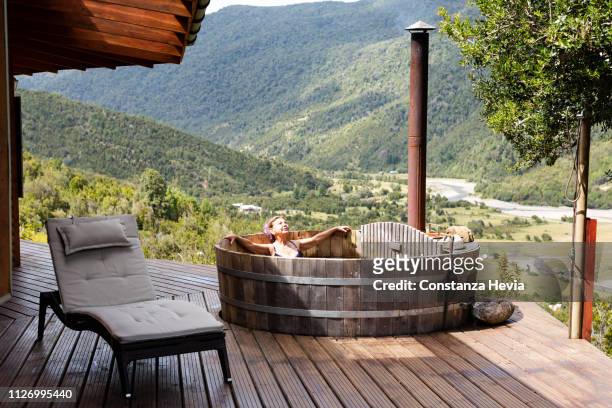 senior woman relaxing in a wooden hot tub - hot tub stock pictures, royalty-free photos & images