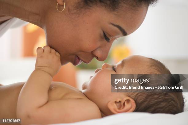 mixed race mother talking to baby - chest kissing stockfoto's en -beelden