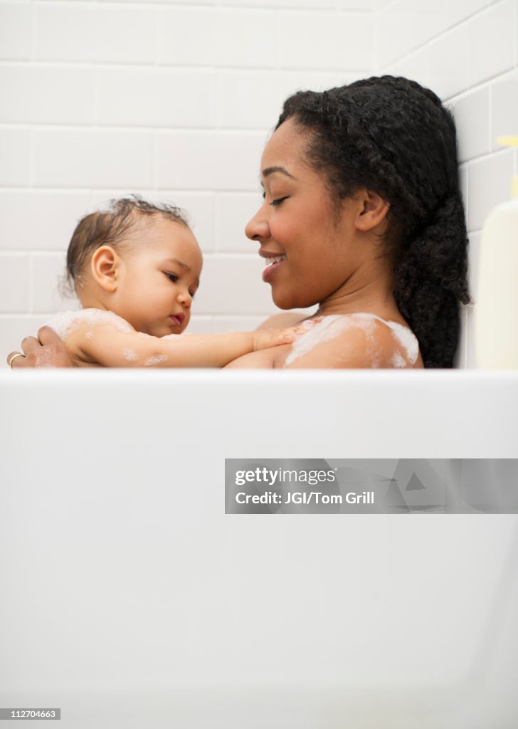 Mixed race woman bathing with baby