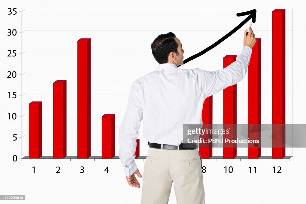 Hispanic businessman drawing bar graph on board