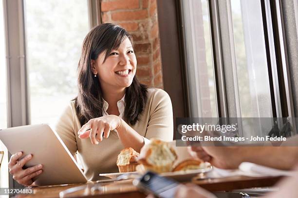 chinese woman using digital tablet in cafe - enjoying coffee cafe morning light stock pictures, royalty-free photos & images