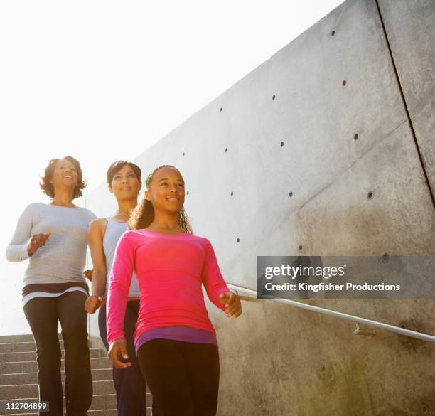 smiling grandmother, mother and daughter descending steps - family tree stockfoto's en -beelden