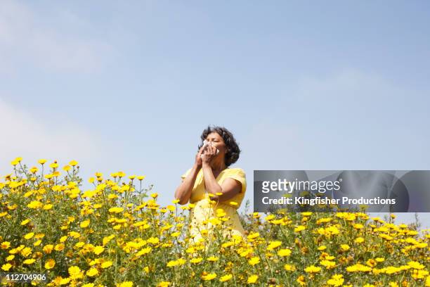 mixed race woman in field of flowers enjoying scent - アレルギー ストックフォトと画像