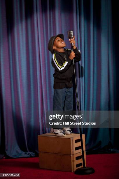 black boy on crate singing into microphone - boy singing stock-fotos und bilder
