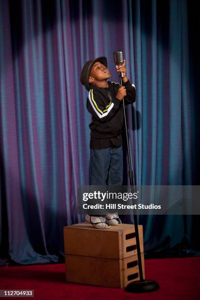 black boy on crate singing into microphone - black curtain stock pictures, royalty-free photos & images