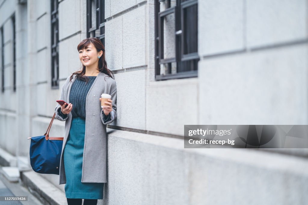 女商人在街上拿著咖啡的肖像