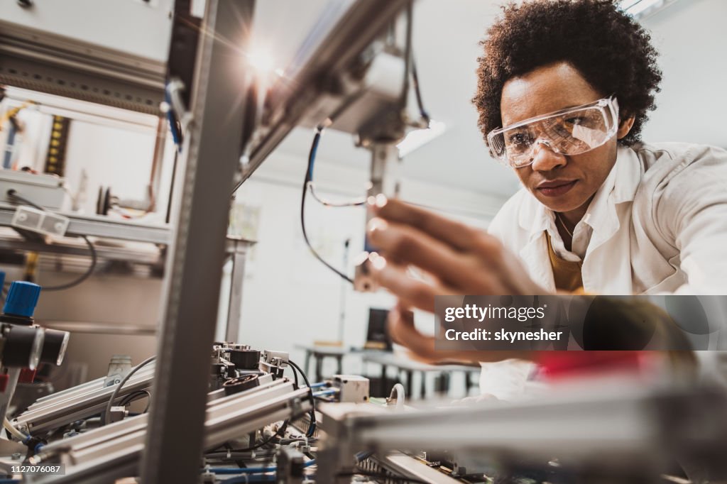 Schwarze weibliche Ingenieur an industrielle Maschine in einem Labor arbeiten.