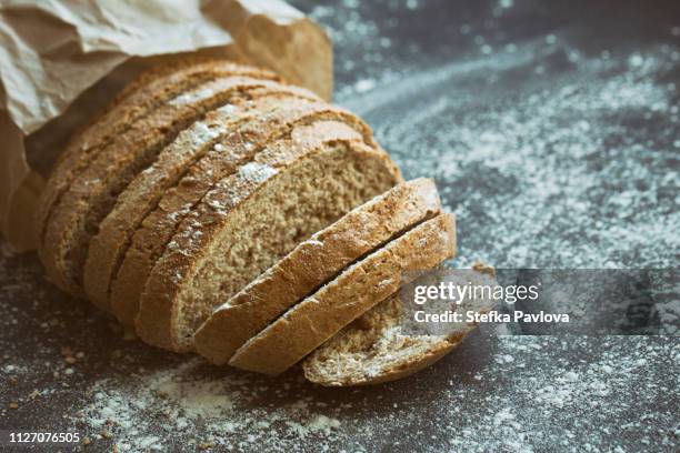 fresh sliced whole grain loaf of bread in a paper bag - celiac disease stock-fotos und bilder