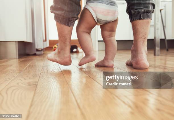 vader onderwijs baby te lopen - uitzicht achterzijde - houten vloer stockfoto's en -beelden