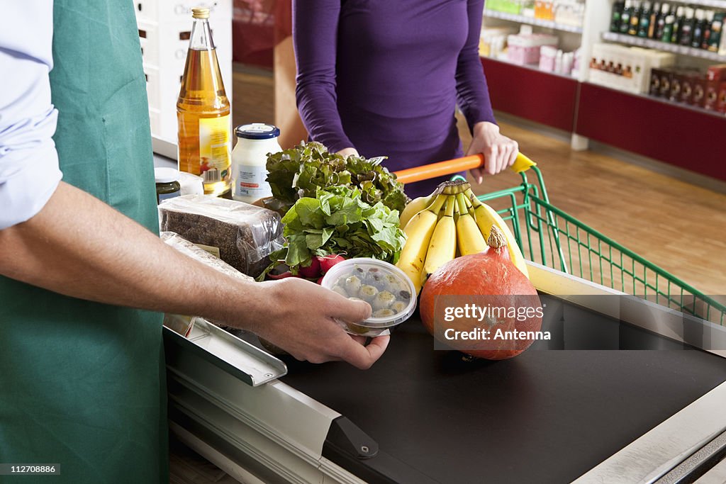A cashier and customer at the checkout line of a supermarket, midsection