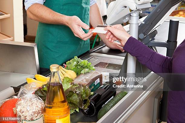 a customer handing a cashier a credit card at the supermarket - female supermarket stock-fotos und bilder