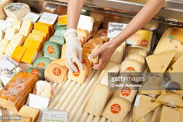 a sale clerk in a cheese shop, focus on hands - cheeses stock-fotos und bilder