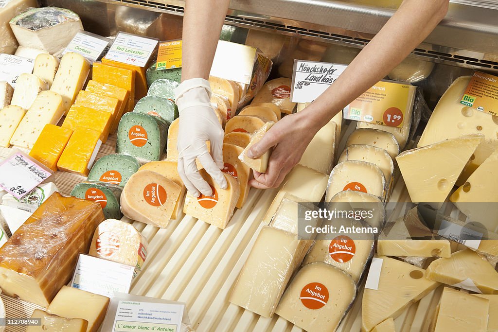 A sale clerk in a cheese shop, focus on hands