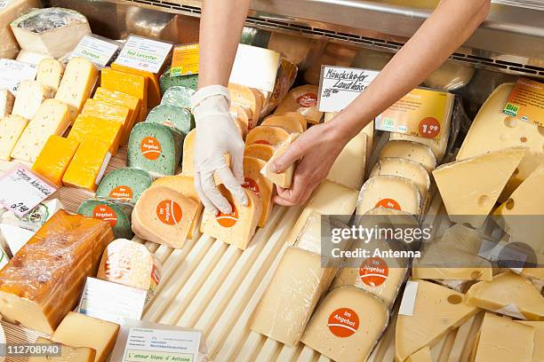 a sale clerk in a cheese shop, focus on hands - delicatessen stock pictures, royalty-free photos & images