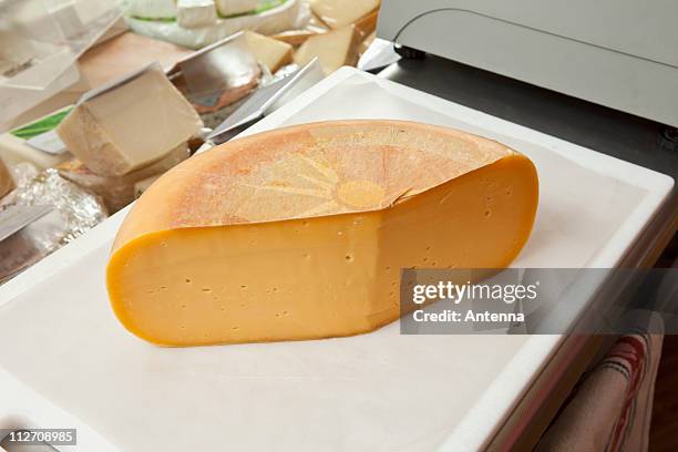 a cheddar cheese wheel - käselaib stock-fotos und bilder