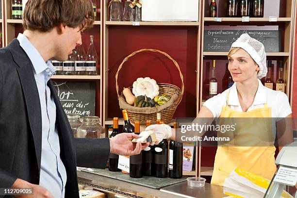 a sales clerk handing a customer a wedge of cheese - cheese wedge foto e immagini stock