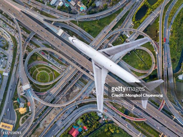 top view airplane flying over highway road junctions. the intersecting freeway road overpass the eastern outer ring road of bangkok, thailand. - crossroad top view stockfoto's en -beelden