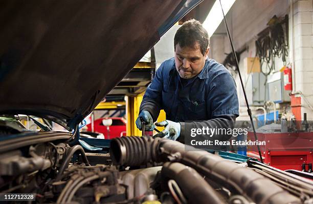 mechanic fixes engine - oficina automóvel imagens e fotografias de stock