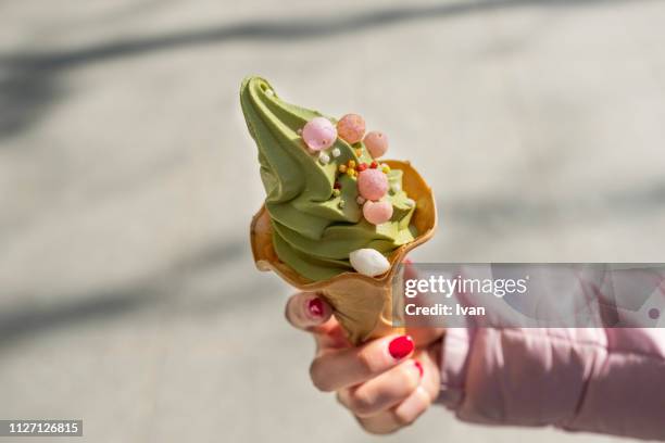 woman holding  a japanese green tea ice cream with dango - mochi stock-fotos und bilder