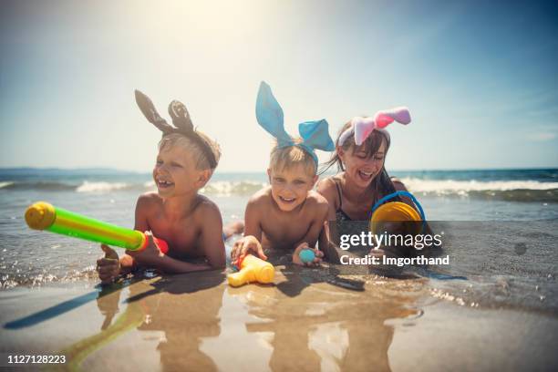 kinderen spelen strand versie van eieren zoeken met pasen - waterpistool stockfoto's en -beelden