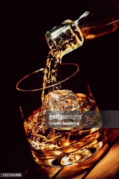 pouring a glass of whiskey on ice - whiskey stock pictures, royalty-free photos & images