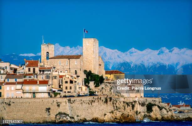 old town of antibes surrounded by the mediterranean sea, snow covered alps in the backdrop - antibes stock-fotos und bilder