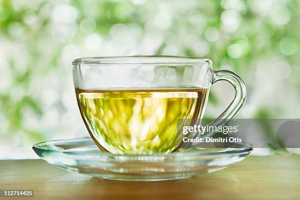 herbal tea in a glass cup and saucer outdoors - herbal tea fotografías e imágenes de stock