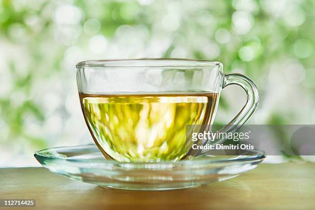herbal tea in a glass cup and saucer outdoors - ハーブティー ストックフォトと画像