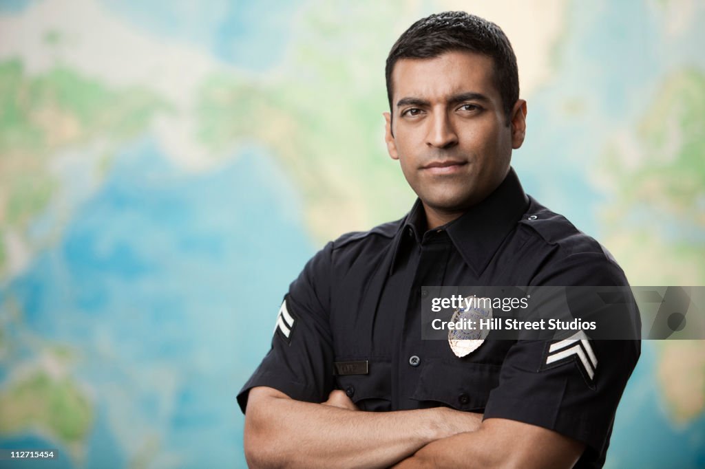 Serious Hispanic policeman with arms crossed