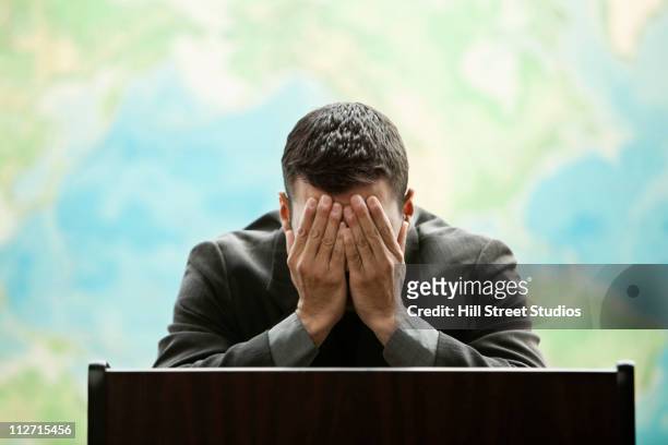 frustrated hispanic businessman standing at podium - angry politician stock pictures, royalty-free photos & images