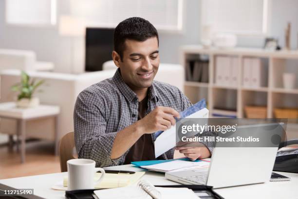 hispanic man opening mail in home office - open day one stock pictures, royalty-free photos & images