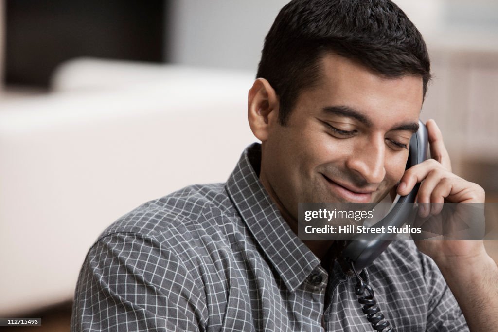 Hispanic man using telephone in home office