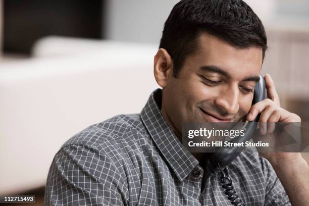 hispanic man using telephone in home office - landline phone home stock pictures, royalty-free photos & images